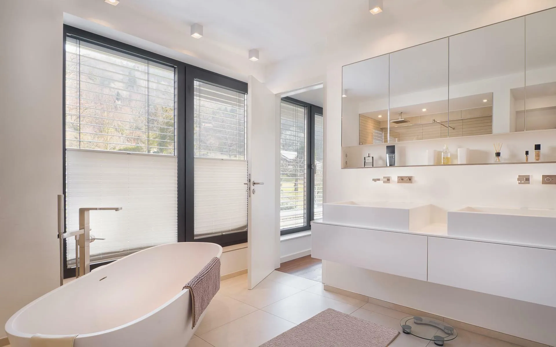 Modernes Badezimmer mit Doppelwaschplatz, großen Fenstern und freistehender Badewanne in heller Optik.