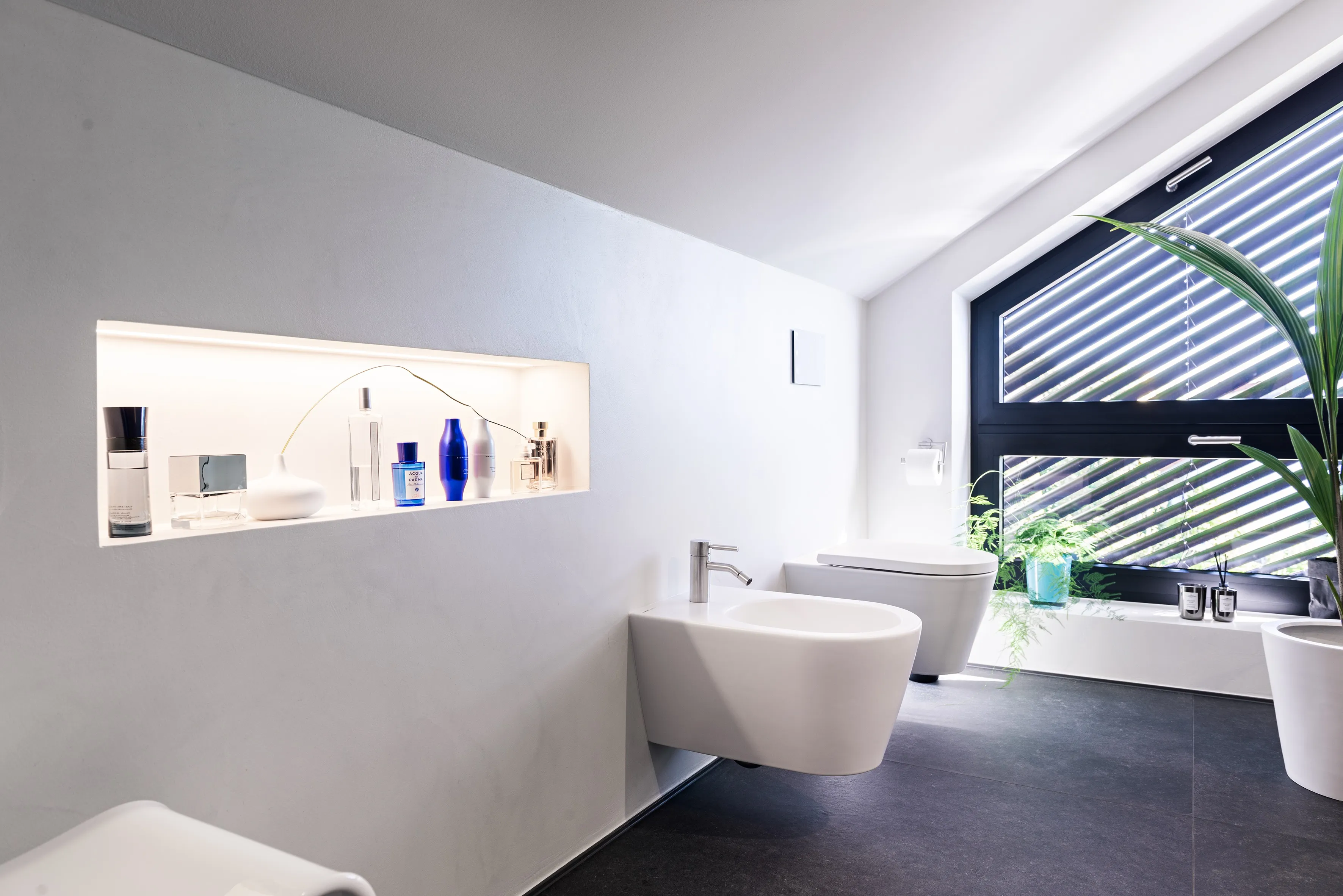 Modernes Badezimmer mit Bidet, wandhängendem WC und großem Fenster mit schwarzen Rahmen.