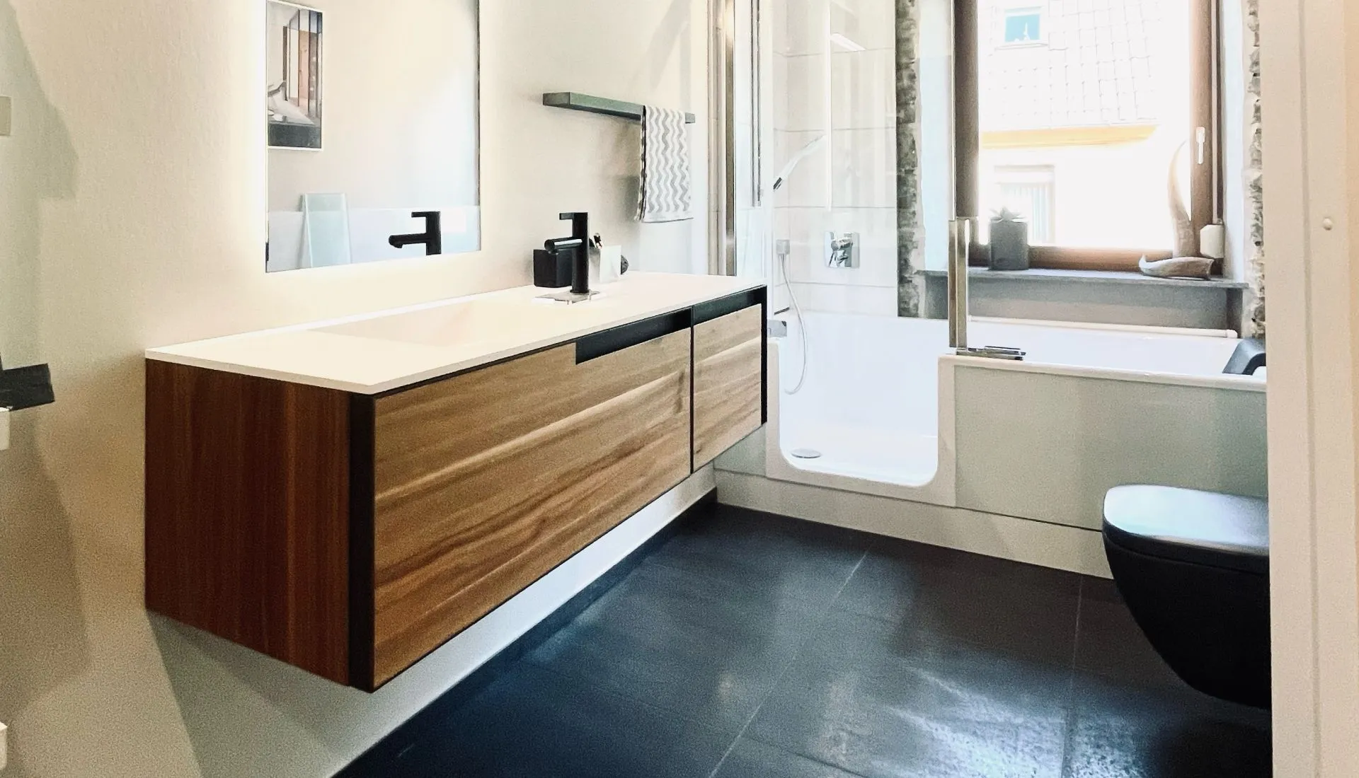 Stilvolles Badezimmer mit Holzwaschtisch, schwarzen Armaturen und sichtbaren Deckenbalken.