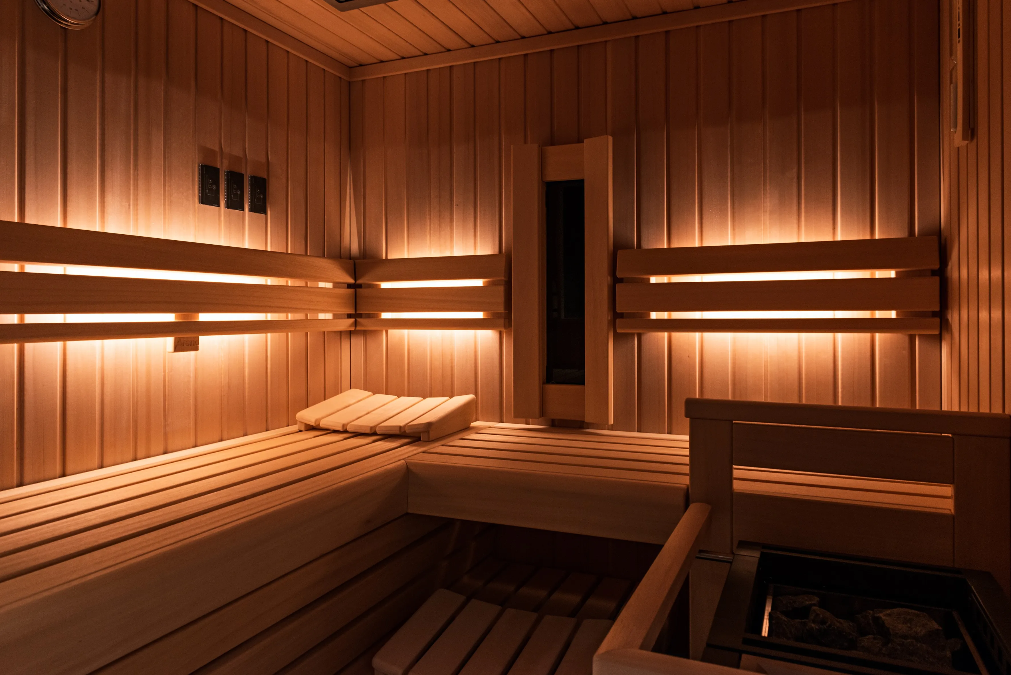 Innenansicht einer finnischen Sauna mit heller Holzverkleidung, indirekter Beleuchtung und großzügigen Sitz- und Liegeflächen.