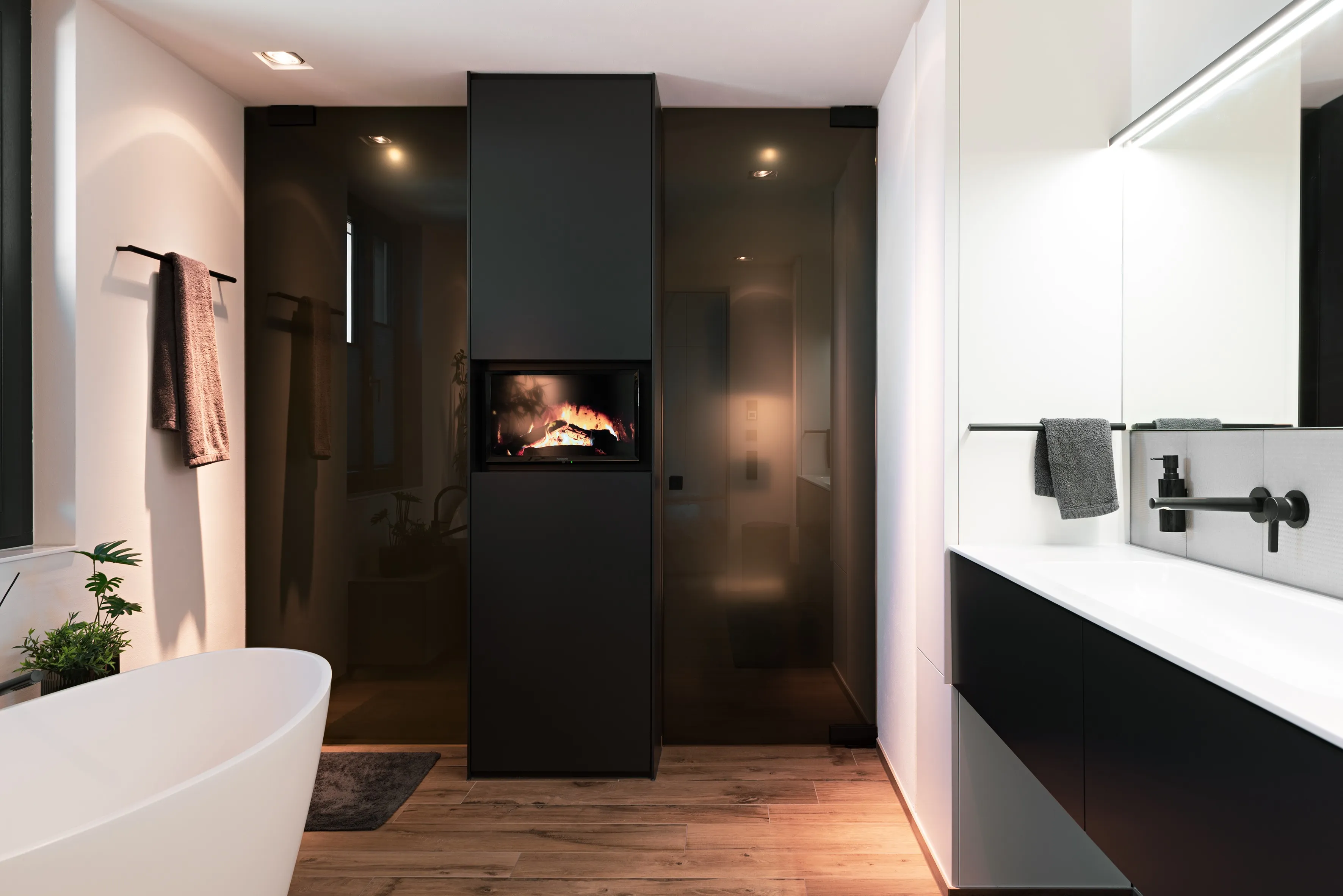 Hochwertiges Badezimmer mit großzügigem Waschtisch, integriertem Kamin und warmen Holzbodenfliesen.