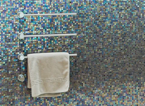 Dusche mit Handtuchhalter an einer Wand mit Mosaik-Fliesen.