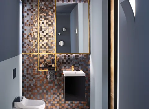 Elegantes Bad mit Wand-WC Geberit AquaClean Tuma, Mosaikfliesen und einem schmalen, goldgerahmten Spiegel. Dezente Beleuchtung schafft eine warme Atmosphäre.
