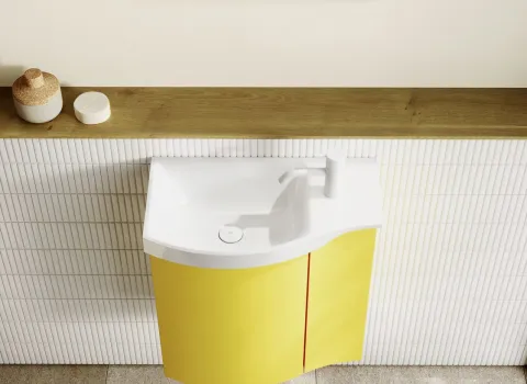 Ein kompakter Gästebadwaschtisch der Serie Sinea 3.0 in leuchtendem Gelb ist platzsparend an eine geflieste Wand montiert.