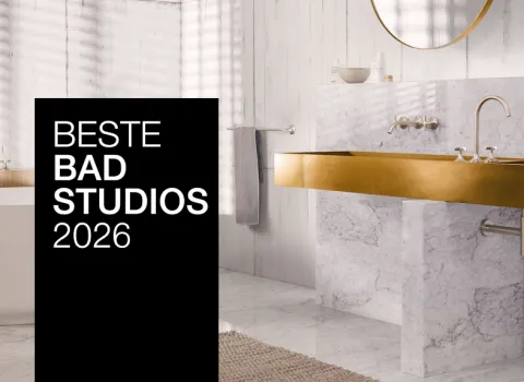 Ein stilvolles Bad mit goldenen Armaturen, Marmorwaschtisch und freistehender Badewanne. Ein schwarzer Banner mit "Beste Badstudios 2026" ist prominent im Bild.