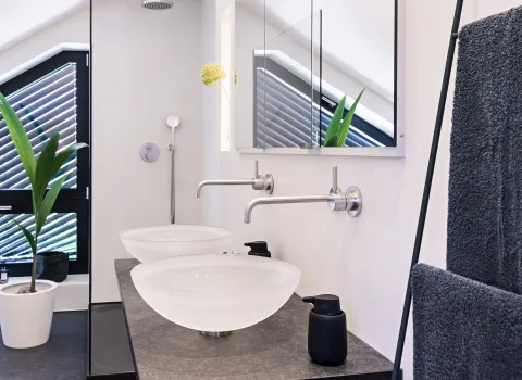 Modernes Dachbad mit Doppelwaschtisch, schwarzen Natursteinplatten und bodengleicher Glasdusche.