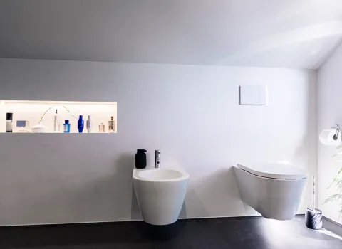 Badezimmer mit wandhängendem WC, Bidet und beleuchteter Wandnische in minimalistischem Design.