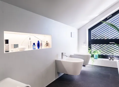 Modernes Badezimmer mit Bidet, wandhängendem WC und großem Fenster mit schwarzen Rahmen.