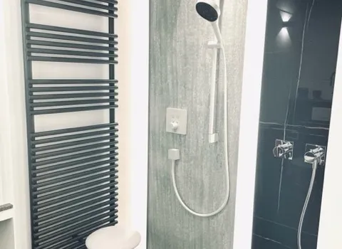 Moderne bodengleiche Dusche mit Regendusche, Handbrause und Handtuchheizkörper in der Ausstellung.