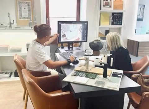 Kundenberatung in der Badausstellung mit digitaler Planung eines modernen Badezimmers am Bildschirm.