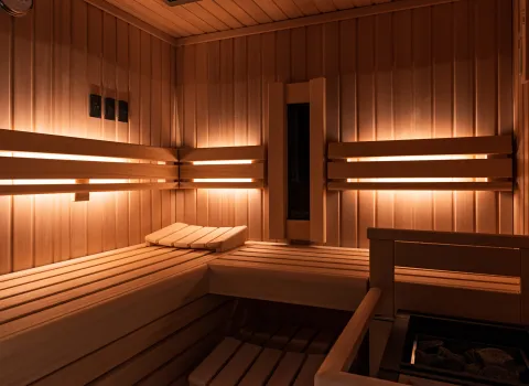 Innenansicht einer finnischen Sauna mit heller Holzverkleidung, indirekter Beleuchtung und großzügigen Sitz- und Liegeflächen.