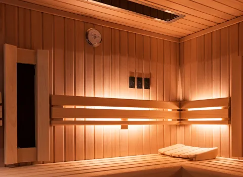 Detailansicht der Sauna mit Holzbänken, stimmungsvoller Beleuchtung und klassischer Saunaausstattung.
