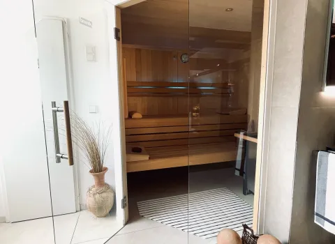 Hochwertige Sauna mit Glasfront, integriert in ein modernes Wellnessbad mit heller Gestaltung.