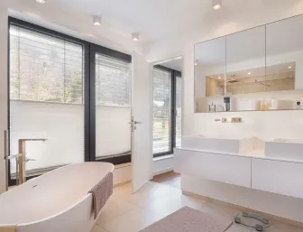 Modernes Badezimmer mit Doppelwaschplatz, großen Fenstern und freistehender Badewanne in heller Optik.