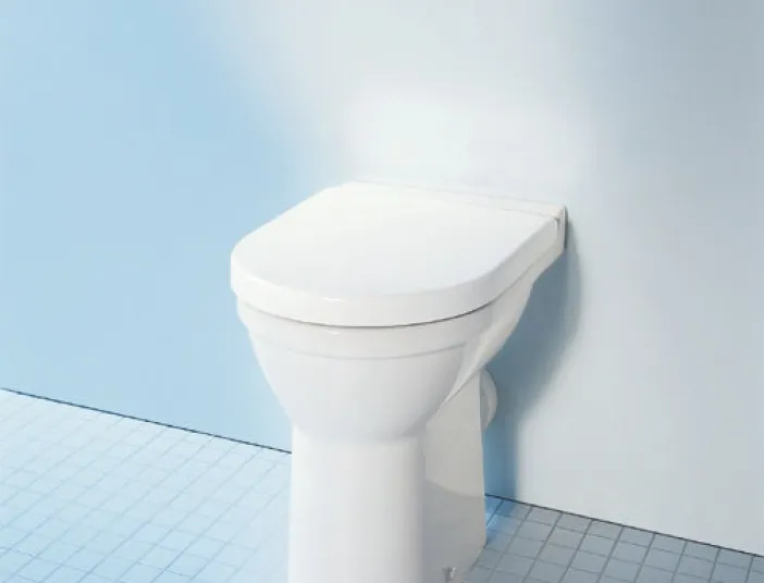 Klassiches Stand-WC mit Unterputzspülung vor weißer Wand.