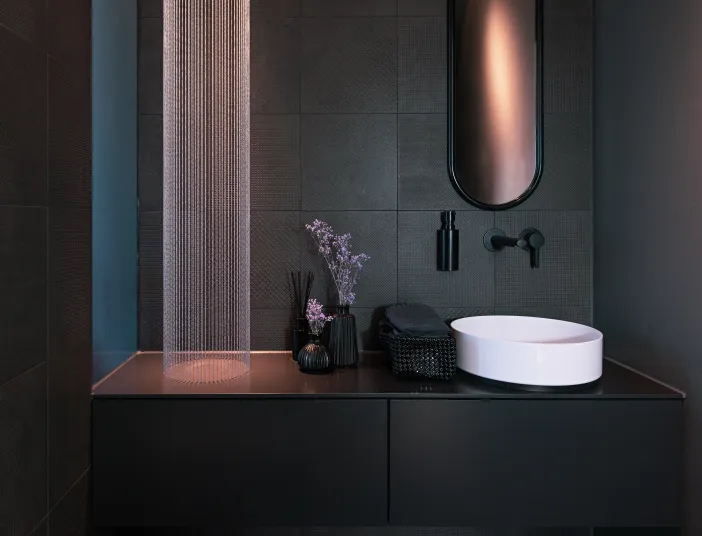 Elegantes Gästebad mit weißem Aufsatzwaschbecken, schwarzen Möbeln und dekorativer Beleuchtung.