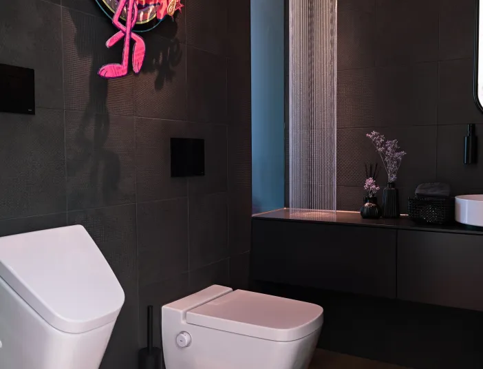Individuell gestaltetes Gäste-WC mit Pink-Panther-Wanddekor, dunklen Fliesen und modernem Waschtisch.