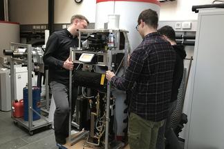 Drei Männer positionieren ein Solvis-Technik-Modul.